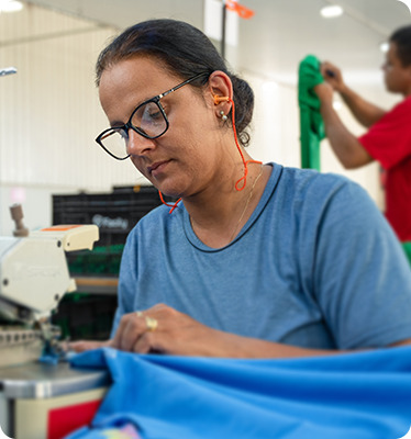 Funcionária costurando tecido em máquina industrial na fábrica da Dimatex.